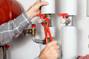 Plombier en action dans un local technique travaillant sur une installation de chauffage